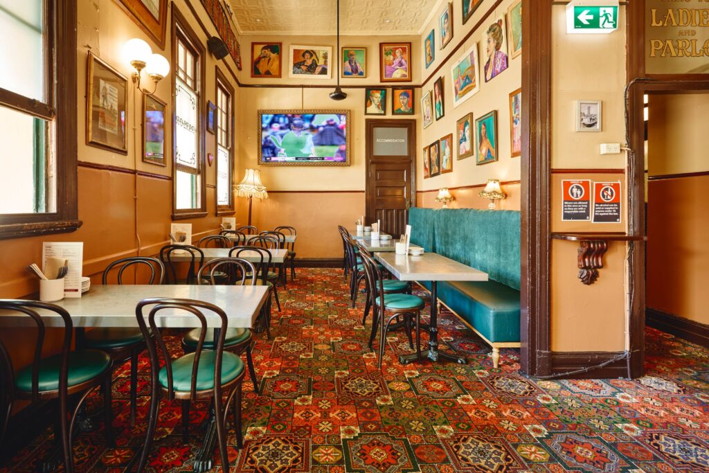 Heritage-style dining room at The Australian Heritage Hotel with patterned carpet, booth seating, and gallery wall artwork