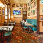 Heritage-style dining room at The Australian Heritage Hotel with patterned carpet, booth seating, and gallery wall artwork