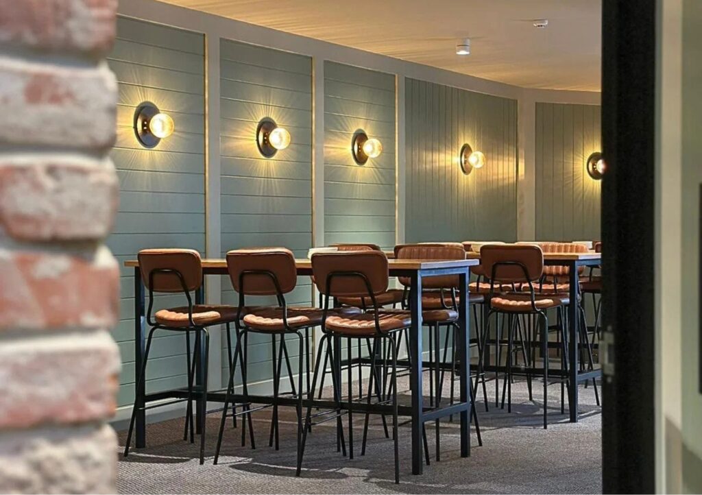 The Back Room function space at Settlers Inn Port Macquarie with high tables, bar stools and warm wall lighting.