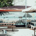 Outdoor beer garden at Settlers Inn Port Macquarie featuring picnic tables, umbrellas, festoon lights and a colourful wall mural.
