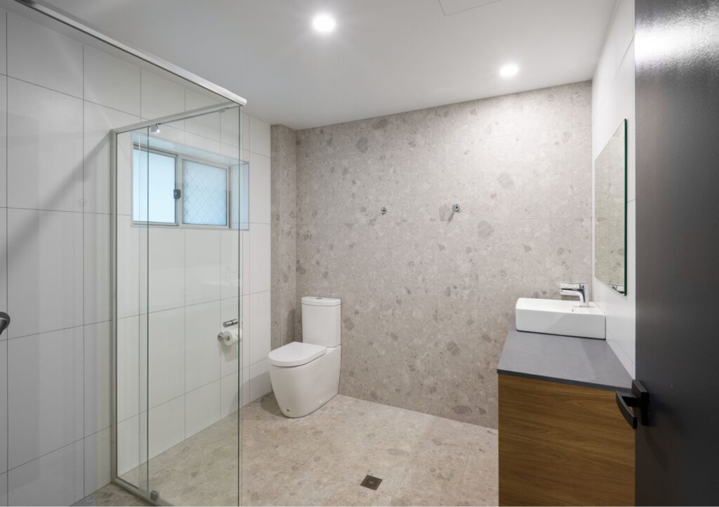 Modern bathroom in the Superior Large Family Room at Settlers Inn Port Macquarie, with glass shower, toilet, vanity and tiled finishes.