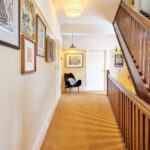 Interior hallway at Darlo Bar accommodation in Darlinghurst featuring original timber staircase and artwork.