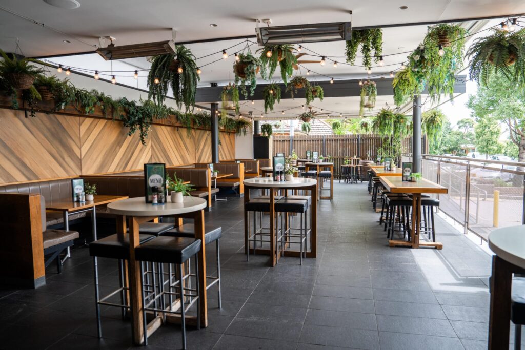 Terrace at Camden Hotel NSW featuring outdoor dining, hanging greenery, booth seating, and a relaxed atmosphere for drinks and casual dining.